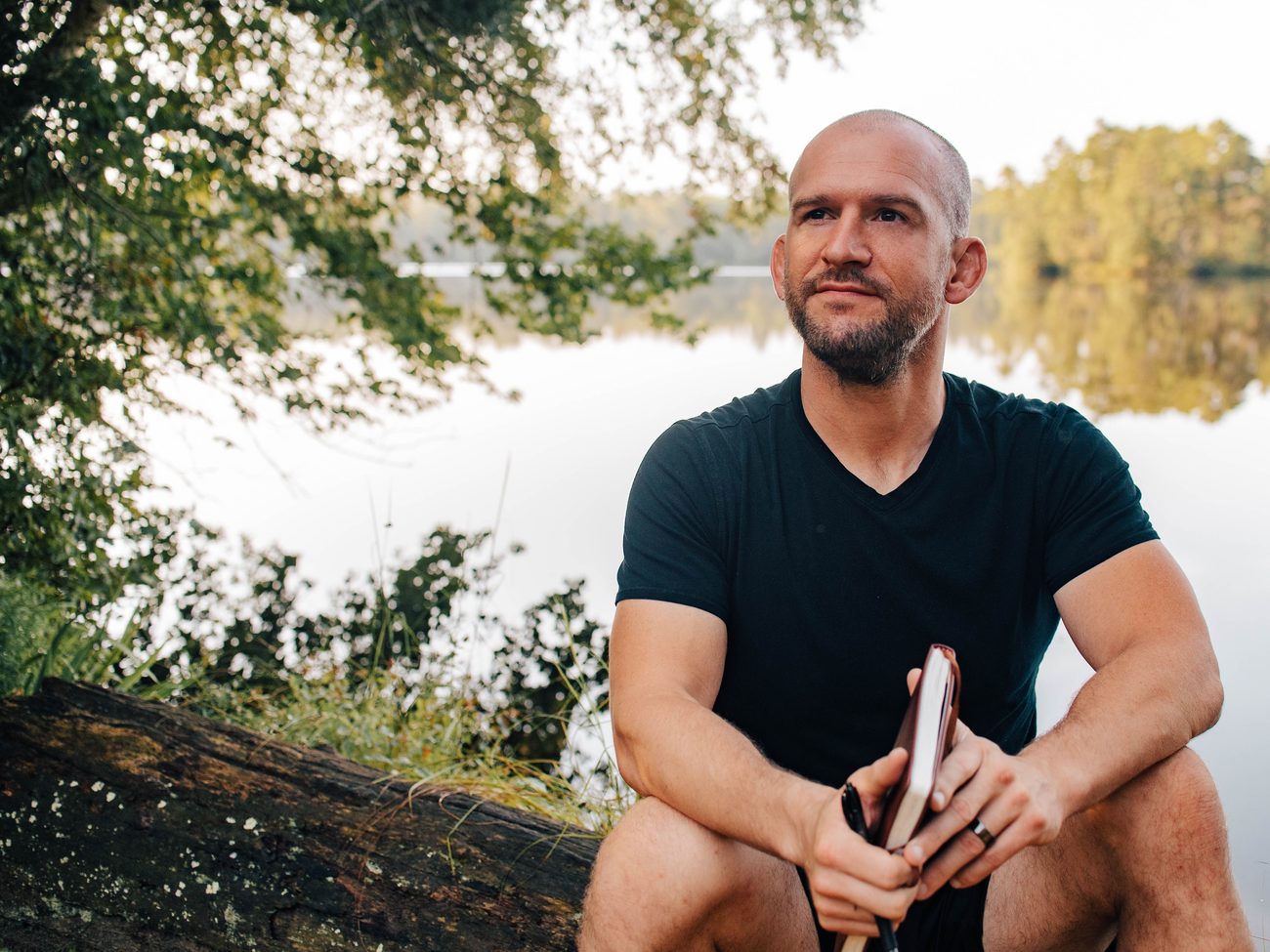Chris Matakas sitting by a lake with a book