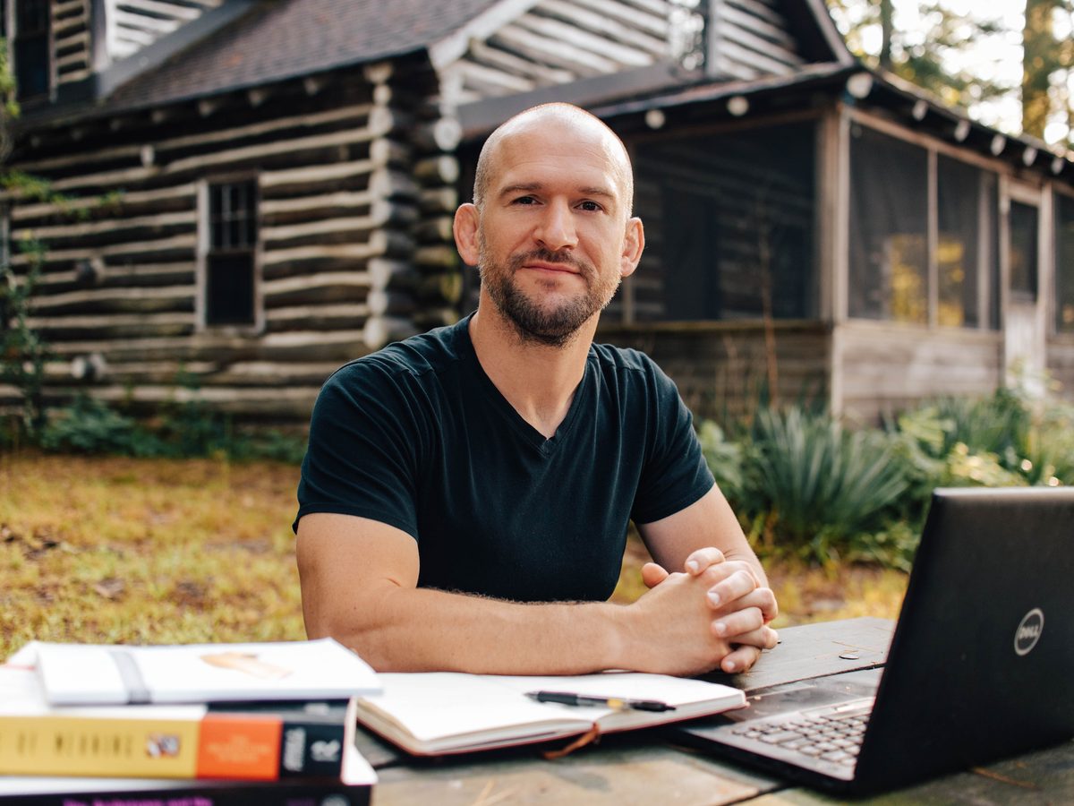Chris Matakas at an outdoor table with his books and laptop, smiling