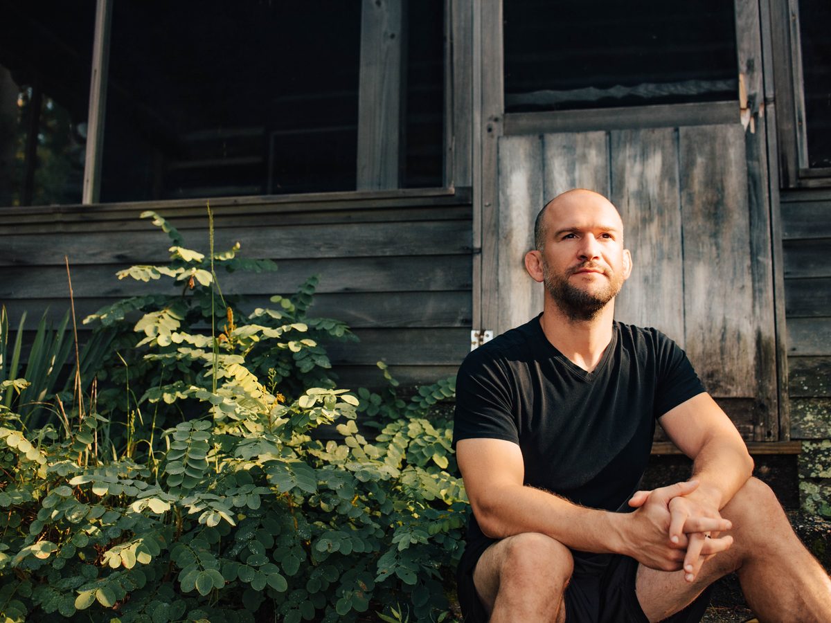 Chris Matakas sitting outside a log cabin