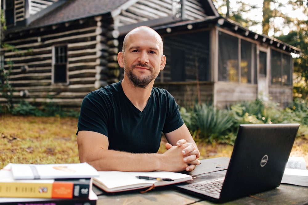 Chris Matakas at an outdoor table with his books and laptop, smiling
